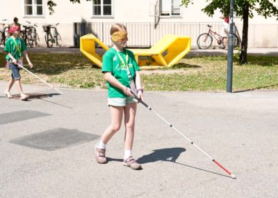 Kinder probieren in einer Lehrveranstaltung das Gehen mit Blindenstock