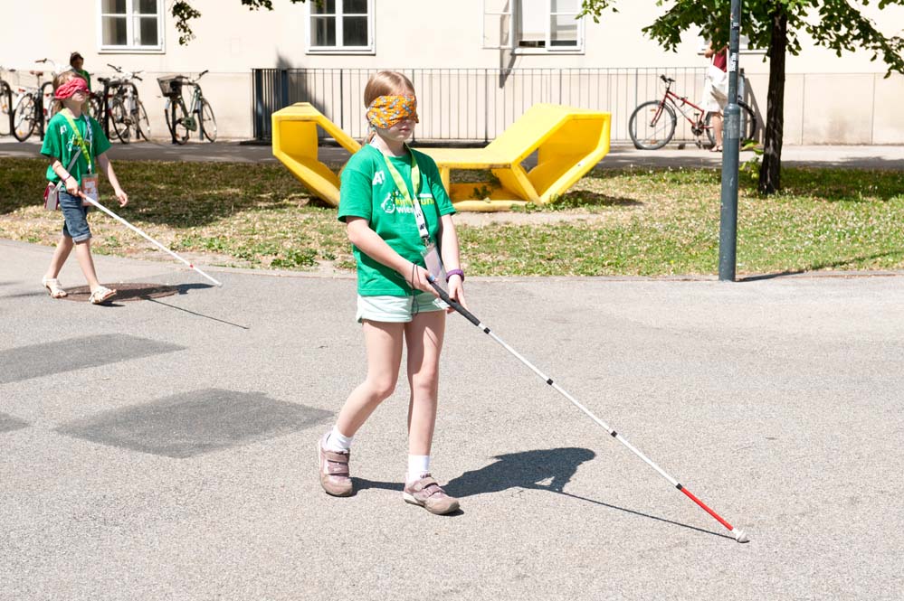 Children try out walking with a blind man's stick in a course