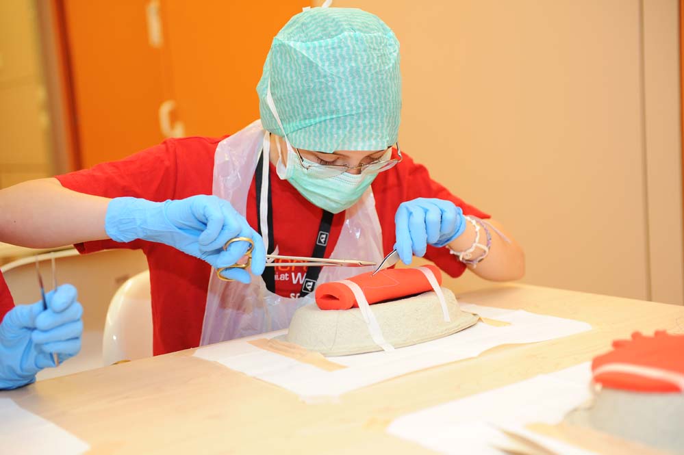 Vienna Children's University student in surgery workshop practises using scissors and tweezers