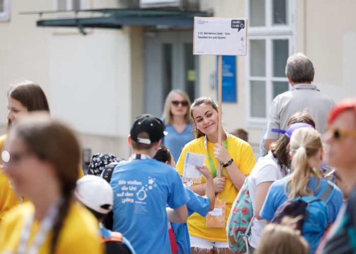 beim Treffpunkt wird ein Lehrveranstaltungsschild von einem Teammitglied hochgehalten