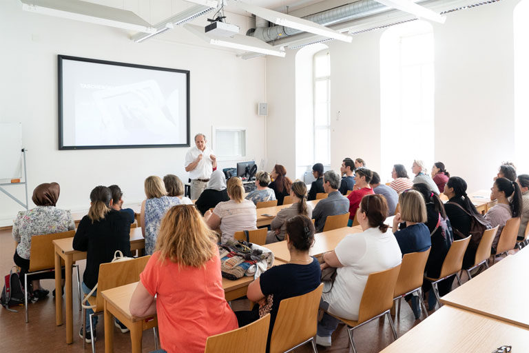 Beim Elternprogramm lauschen Erwachsene gespannt einem Vortrag im Seminarraum.