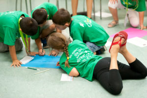 Kinder gestalten am Boden sitzend ein Plakat