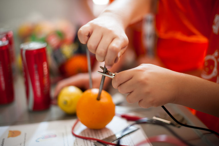 ein Kind werkt mit Obst und technischen Bauteilen