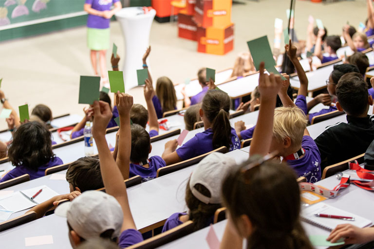 Kinder in einer Vorlesung beantworten Fragen durch Hochhalten von Farbkarten