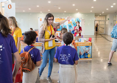 a team member in a yellow T-Shirt shows a child the way