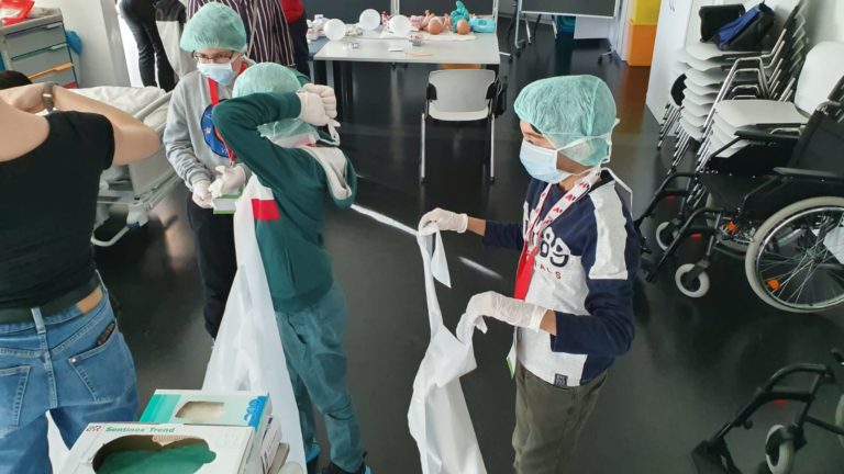 Kinder in einem Medizin-Workshop legen Schutzkleidung an