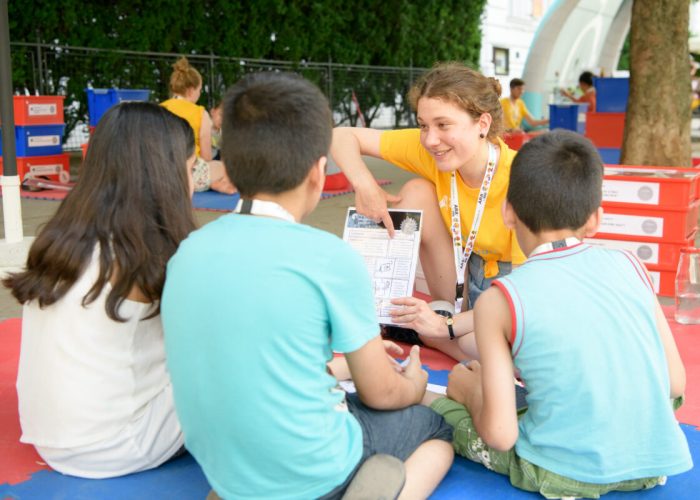 Mitarbeiterin erklärt Kindern ein Experiment