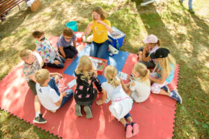 eine Gruppe Kinder und eine Mitarbeiterin beim Experimentieren