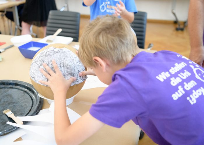 KinderuniWien-Student bastelt Globus in Workshop