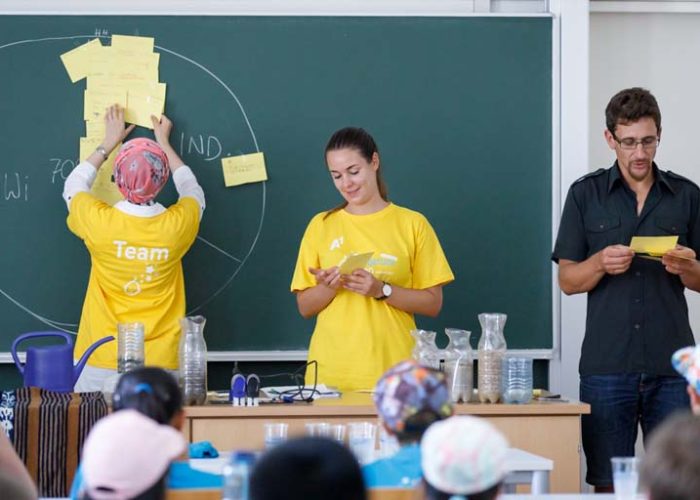Lehrender und Mitarbeiterinnen im Hörsaal