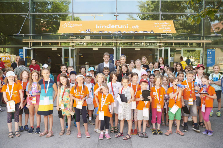 Bildungsminister Martin Polaschek, Vizerektorin Christa Schnabl, Karoline iber und viele KinderuniWien-Studierende vor dem Hörsaalzentrum