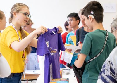 ein KinderuniWien-Student mit Hörgerät holt sein T-Shirt ab