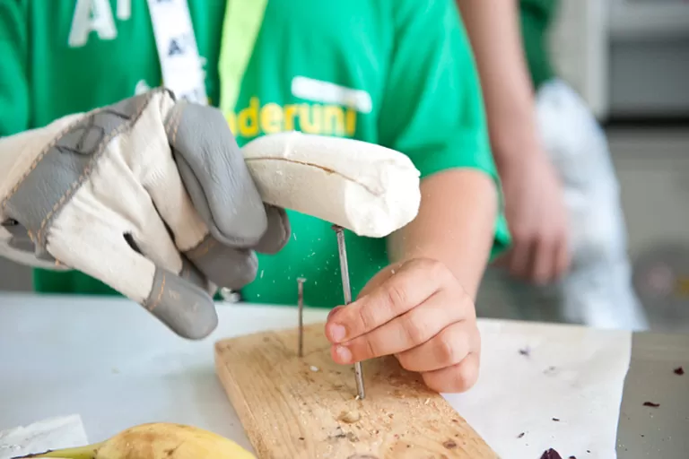 ein Kind benutzt eine gefrorene Banane als Hammer