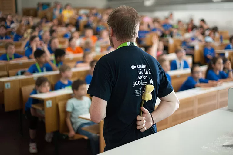 ein Lehrender versteckt Schwamm hinter seinem Rücken